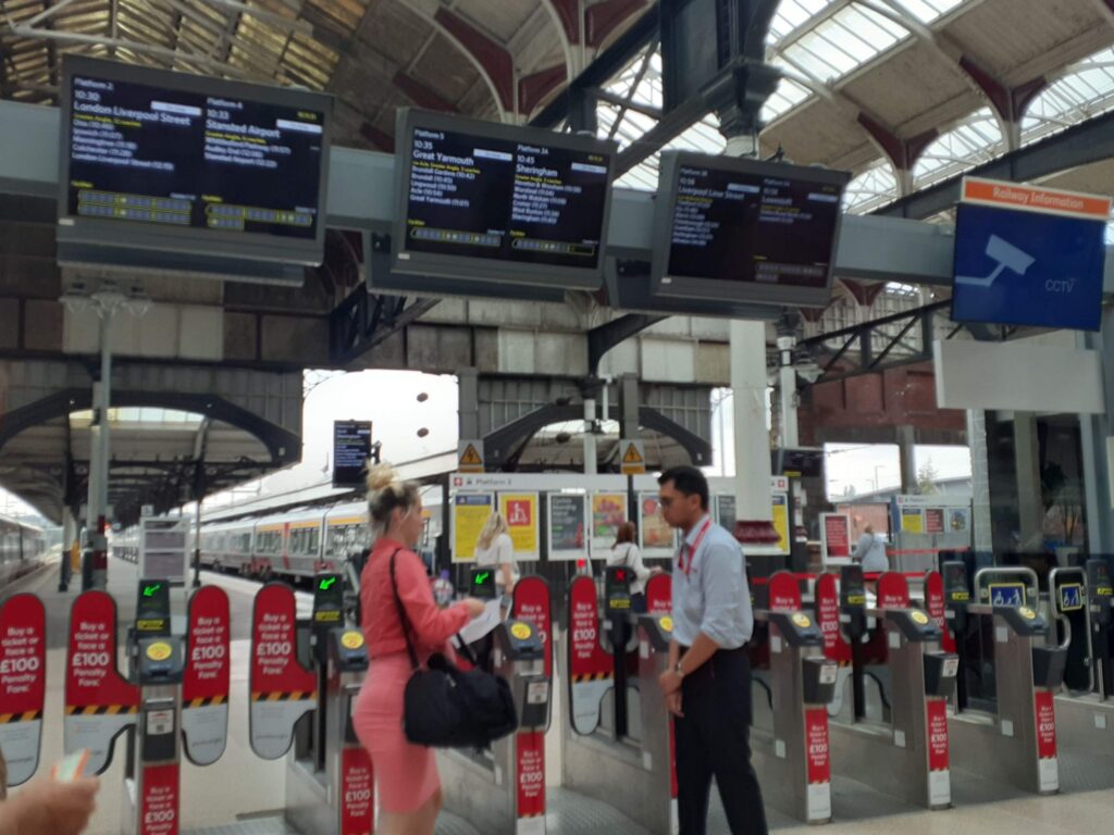 A staff and a customer talking in front of the ticket barrier in at a railway station in the UK 