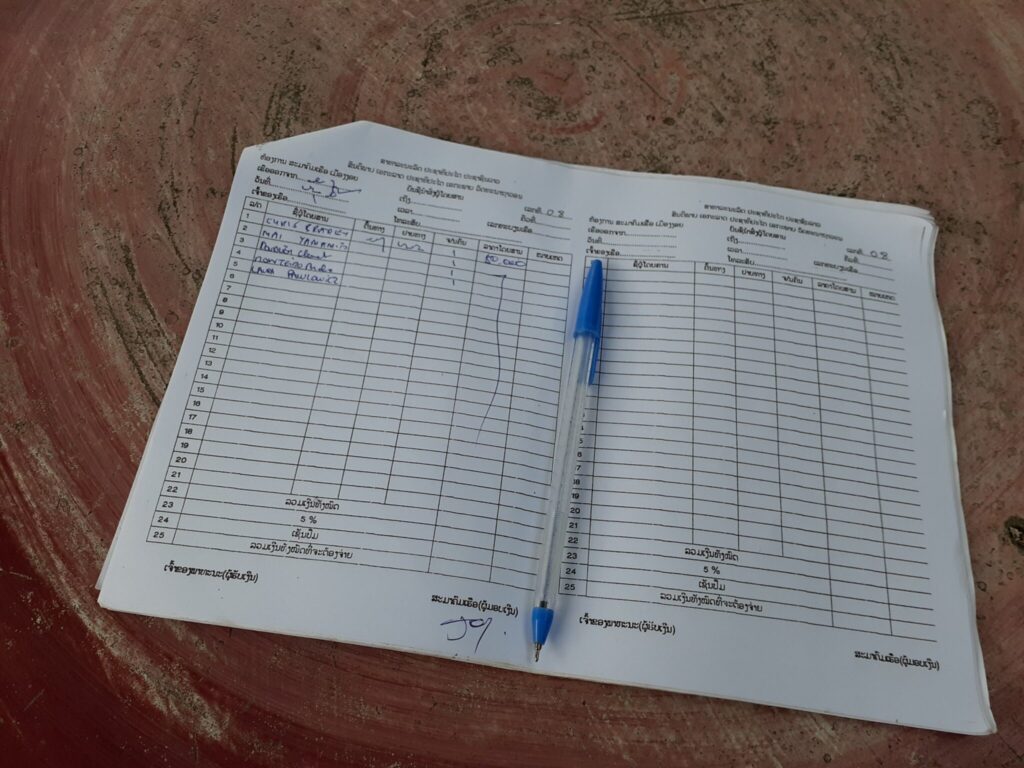 Passenger's names are documented in the notebook at the boat office in Muang Ngoi Pier